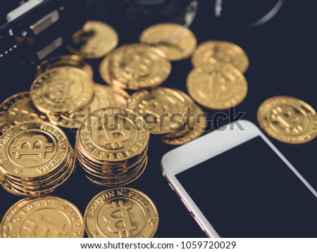 CryptoCurrency concept with stack golden Bitcoins, smartphone, graphics card on black background.