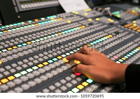 Hands push a button of Switcher buttons in studio TV station, Audio and Video Production Switcher of Television Broadcast.