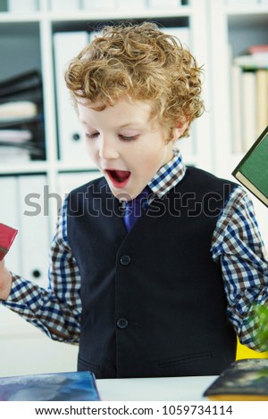 Little Caucasian curly boy chooses a book in the library.