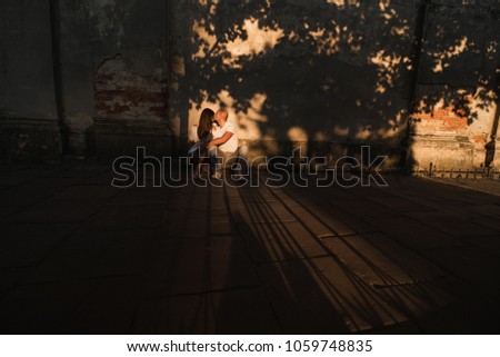 Couple on the sunset. Loving couple against the background of the old wall.