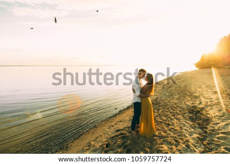Young couple running on a tropical beach at sunset
