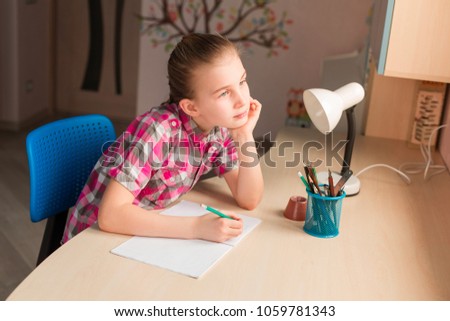 Cute little girl writing her homework at the table