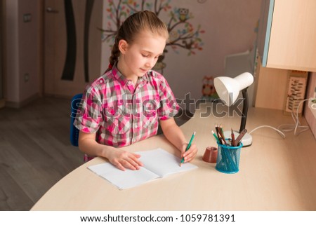 Cute little girl writing her homework at the table