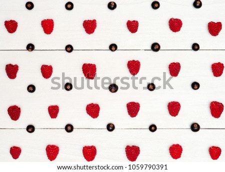 Rows of ripe sweet raspberries and black currant, free space. Fresh berries on white wooden background. Summer, healthy food concept. Berries background