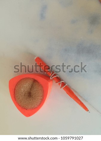 orange Pen and sponge pad on the white desk