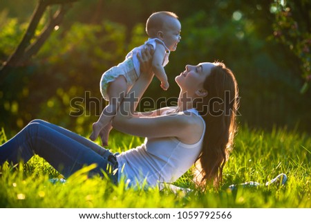 Picture of cute cheerful baby on mother's hands outdoors
