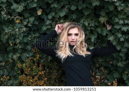 effective and charming girl in leaves posing for a photo and beckoning with her gaze