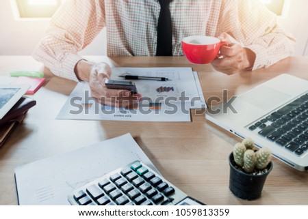 Business man using smart phone in hands touching on a screen and he is sitting on office.
