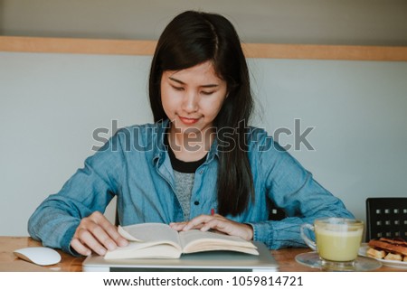Beautiful girl  sitting by wooden table and reading book