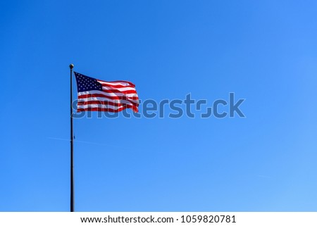 American flag waving against solid blue sky