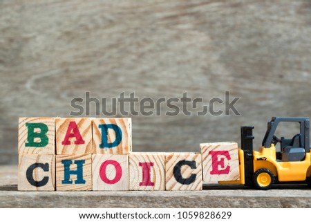 Toy forklift hold letter block E to complete word bad choice on wood background