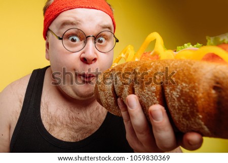 Fat funny man eating unhealthy big burger Royalty-Free Stock Photo #1059830369