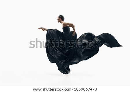 Modern ballet dancer exercising isolated in full body on white studio background. Ballerina or modern dancer in black silk dress dancing on white studio background. Caucasian model dancing barefoot