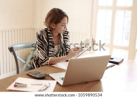 Asian business woman working in in coffee shop cafe with laptop paper work  (Business woman concept.)
