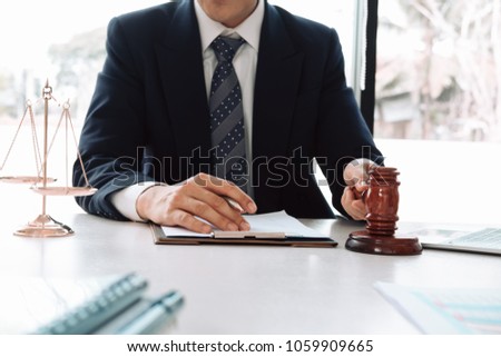 Justice and law concept. Gavel on sounding block in hand's Male judge at a courtroom, working with document law books, report the case on table in modern office.
