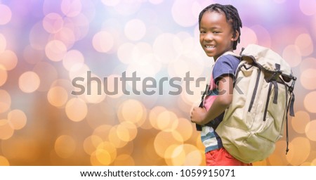 Portrait of happy boy carrying backpack over bokeh