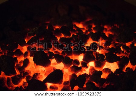 A closeup of burning coals in a furnace burning bright orange