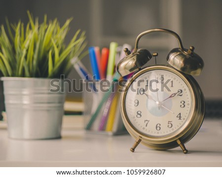 Vintage alarm clock and pen box, flower pot on table desk.