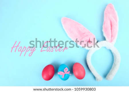 Easter eggs and hare ears on a blue background. Copy space, top view.