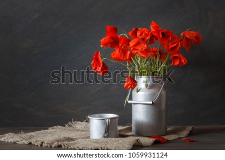 Still life in a rustic style: aluminum cookware and a bouquet of red poppies