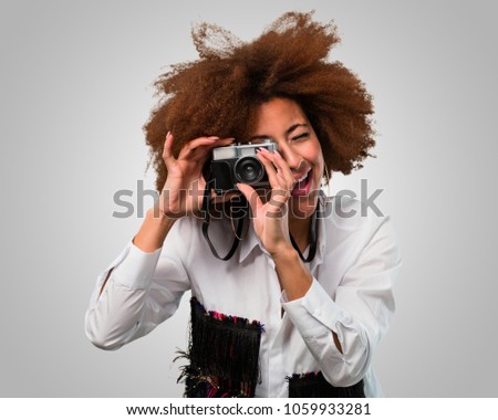 young afro woman taking a photo with a vintage camera