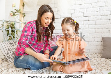 Young mother and her child girl reading a book