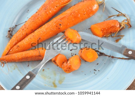 stewed carrots with honey, whole and cut into pieces on a blue plate with Cutlery