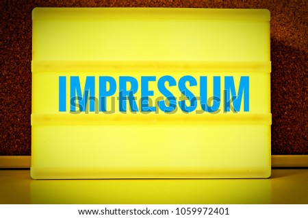 Luminous panel with the inscription in English Imprint, in German Impressum in front of a pin board,, in yellow with Light Blue letters
