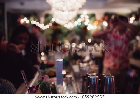 People enjoy the cocktail drinks sitting on the bar counter at the evening cafe. Abstract blurred background