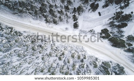 Aerial drone view of road in idyllic winter landscape. Street running through the nature from a birds eye view.