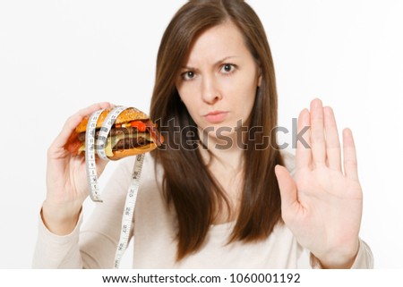 Close up woman holds in hands burger with tailor measuring tape around isolated on white background. Proper nutrition or American classic fast food. Copy space for advertisement. Advertising area