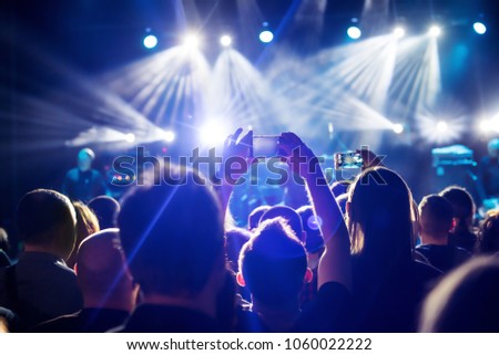 Video recording of the concert on the smartphone phone of the Beach party. Blue conceptual background of the youth party.