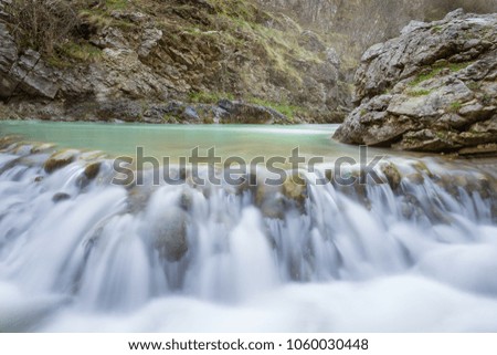 Face to face with a powerful spring mountain creek cascade  in a rocky and misty canyon