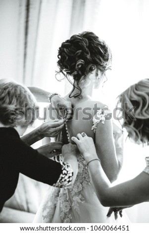Black and white photo. Dressing up a wedding dress for the bridesmaids