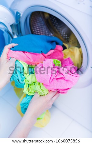Washing machine at bathroom, stainless drum inside with colored clothes.