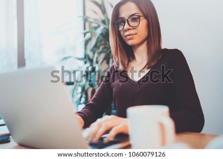 Young entrepreneur girl using mobile laptop for looking a new business solution during work process at night office.Blurred background