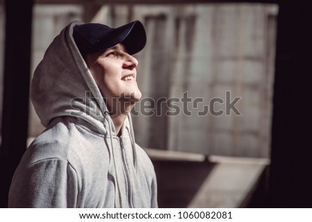 Picture that symbolizes hope. Guy in hoodie looking upwards to light. Royalty-Free Stock Photo #1060082081