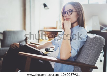 Handsome young blonde wearing glasses and using electronic touch tablet computer on sunny workplace.Horizontal. Blurred background