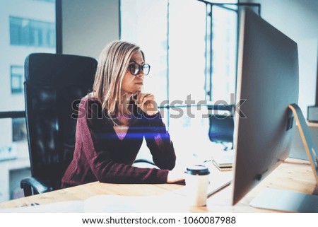 Attractive young businesswoman using desktop computer at modern working place at office.Blurred background.Horizontal