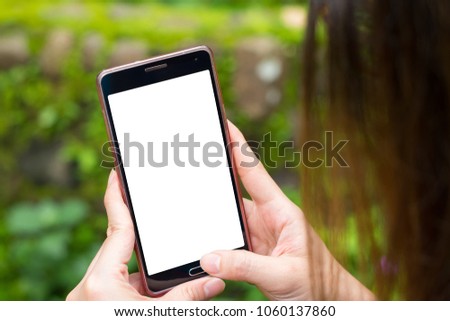 Long hair woman using black smartphone by hands on nature background with daylight, Blank screen with isolated and clipping path, cellphone holding and pressing home button with thumb, Blured backdrop
