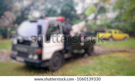 Blurred a police department tow truck help the yellow pickup truck muddy by using a winch with a sling