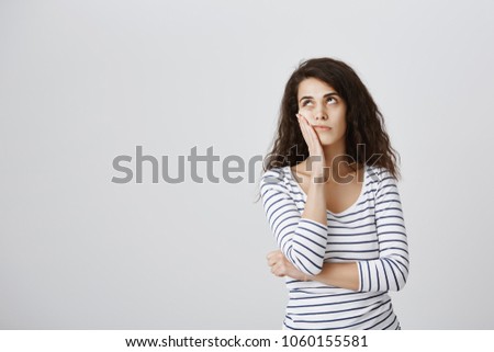 Girl screaming internally from boredom. Cute emotive curly-haired caucasian female making facepalm and rolling eyes from annoyance, hearing nonsense or boring conversation, standing over gray wall
