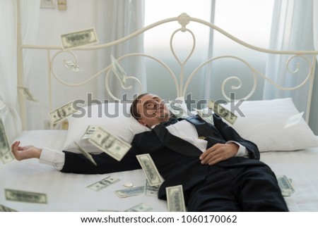Young Businessman with happy, smile on the bed. who are successful in business and many banknote dollars money. business success concept
