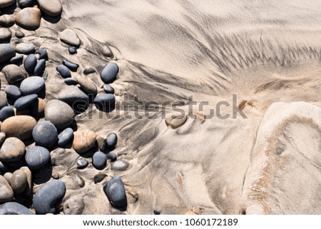 Rocks and sand combine to make abstract patterns on the beach.