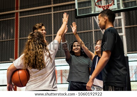 Group of teenager friends on a basketball court giving each other a high five Royalty-Free Stock Photo #1060192922