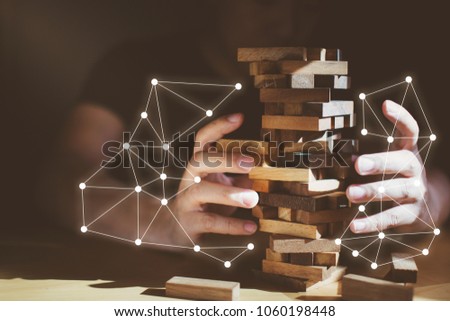 organization ideas concept with hand pull out block of wooden piece from stack strategy and risk concept Royalty-Free Stock Photo #1060198448