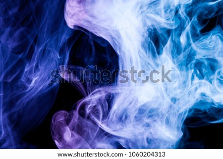Thick colorful smoke of blue, purple on a black isolated background. Background from the smoke of vape