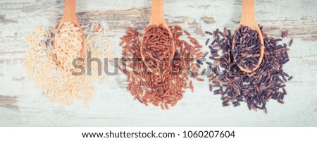 Vintage photo, Brown, black and red rice on wooden spoons on rustic board, concept of healthy, gluten free food and nutrition