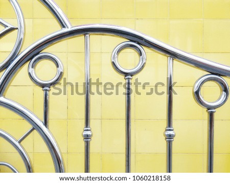Pattern and textile of stainless steel fence with yellow tiles wall background on architecture design concept  