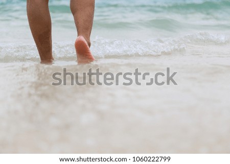 Man walking on sand beach at sunset.